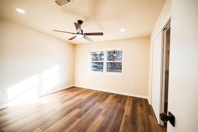 unfurnished bedroom with ceiling fan, dark hardwood / wood-style flooring, a closet, and a textured ceiling