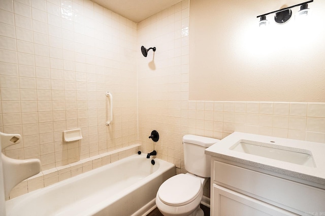 full bathroom featuring tile walls, toilet, tiled shower / bath, and vanity