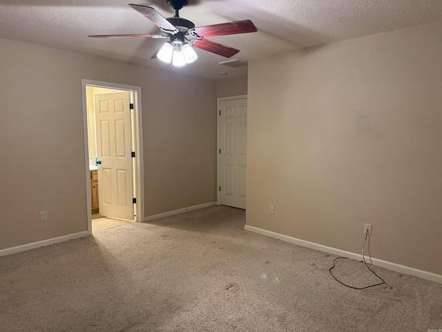 spare room with a textured ceiling, light colored carpet, and ceiling fan