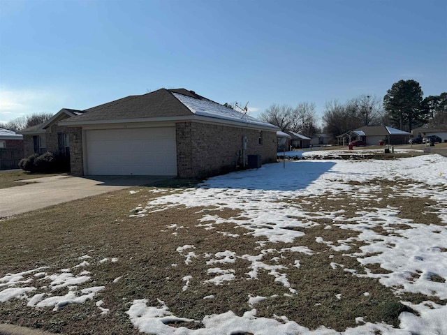 view of snow covered exterior featuring a garage and central AC unit