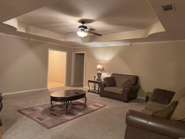 living room featuring a raised ceiling, ceiling fan, crown molding, and light carpet