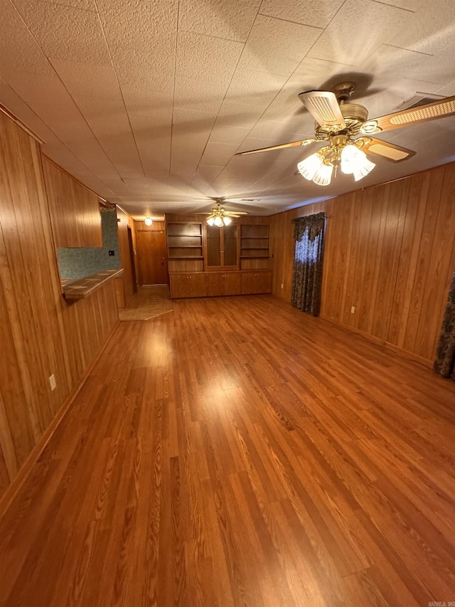 spare room featuring ceiling fan, hardwood / wood-style floors, and wooden walls