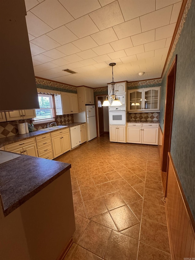 kitchen featuring white appliances, decorative light fixtures, and sink