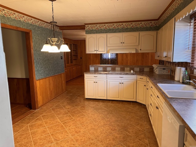 kitchen featuring sink, dishwasher, wood walls, a chandelier, and pendant lighting