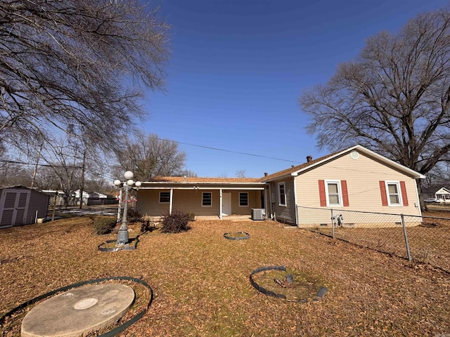 rear view of house with central air condition unit and a shed