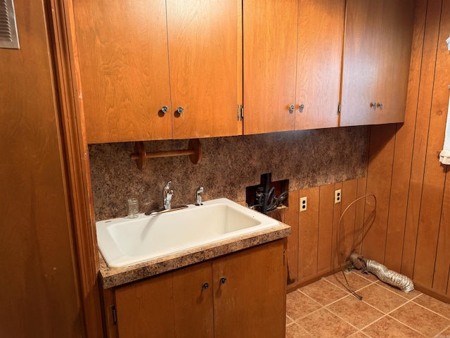 laundry area featuring sink, hookup for a washing machine, cabinets, light tile patterned floors, and wood walls