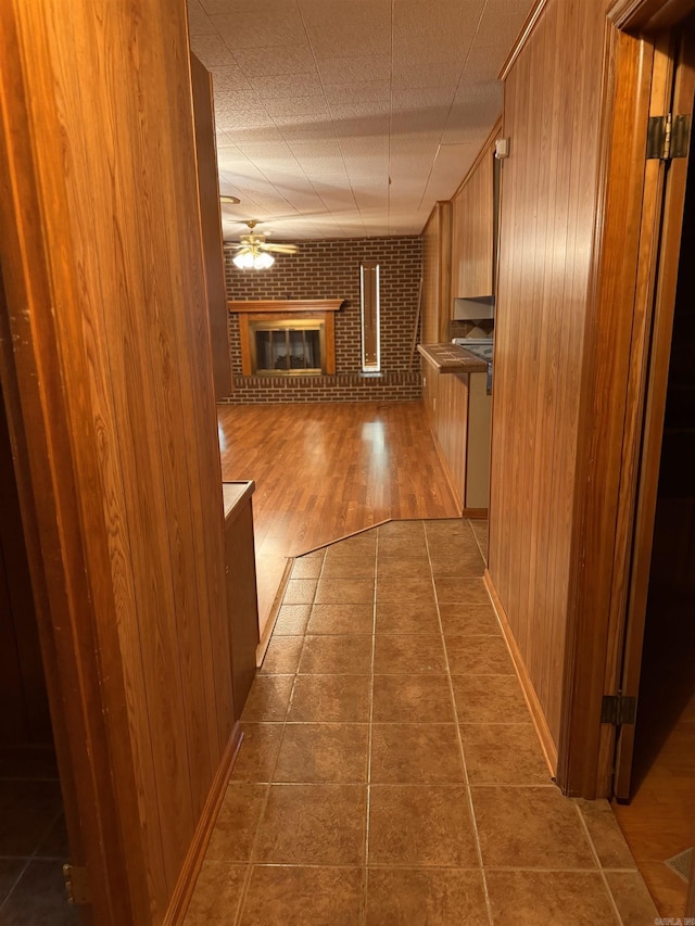 hallway featuring brick wall, wooden walls, and hardwood / wood-style flooring