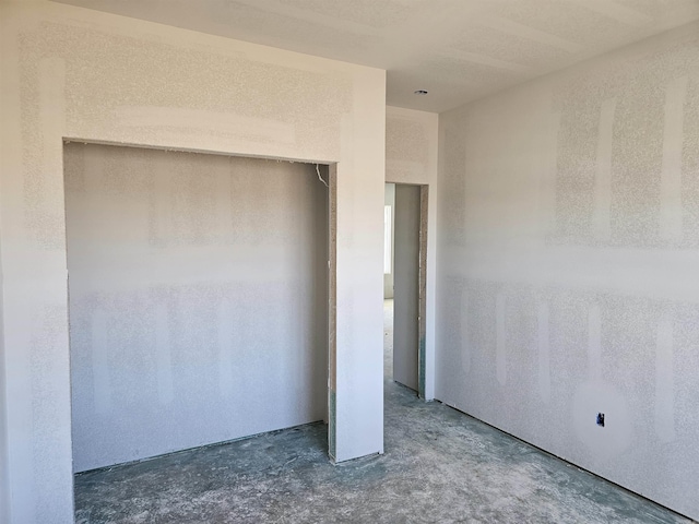 unfurnished bedroom featuring concrete floors and a closet