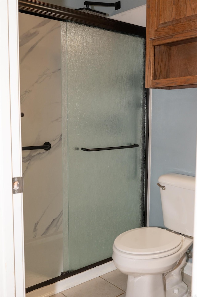 bathroom with toilet, tile patterned flooring, and a shower with door