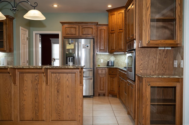 kitchen with light stone countertops, appliances with stainless steel finishes, light tile patterned floors, and tasteful backsplash