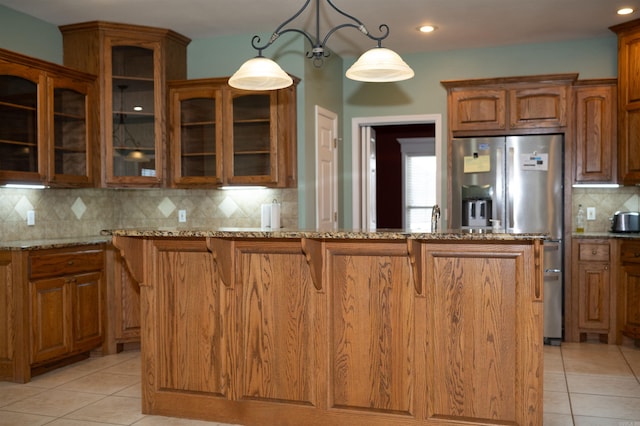 kitchen with hanging light fixtures, backsplash, light stone countertops, and light tile patterned floors