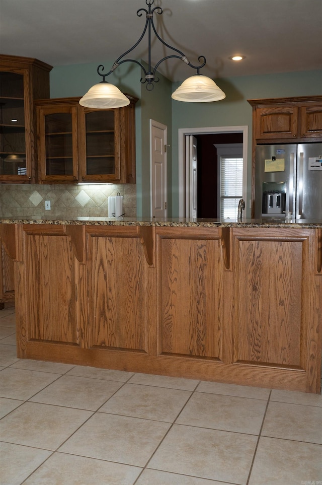 kitchen with light stone countertops, stainless steel fridge with ice dispenser, decorative backsplash, and light tile patterned floors