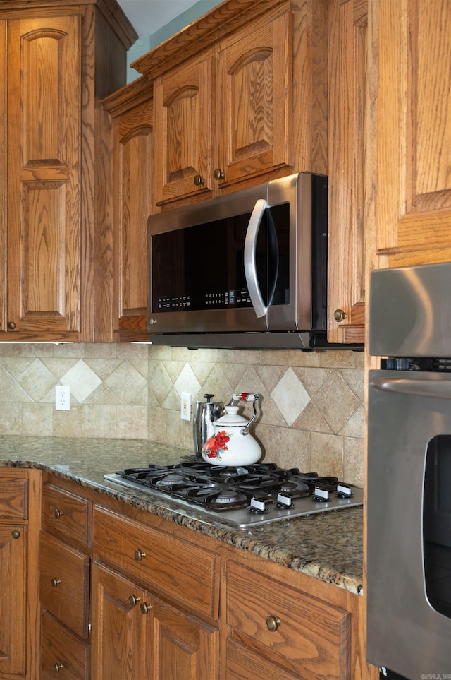 kitchen featuring dark stone counters, stainless steel appliances, and tasteful backsplash