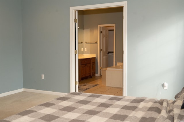 unfurnished bedroom featuring ensuite bath and light tile patterned floors