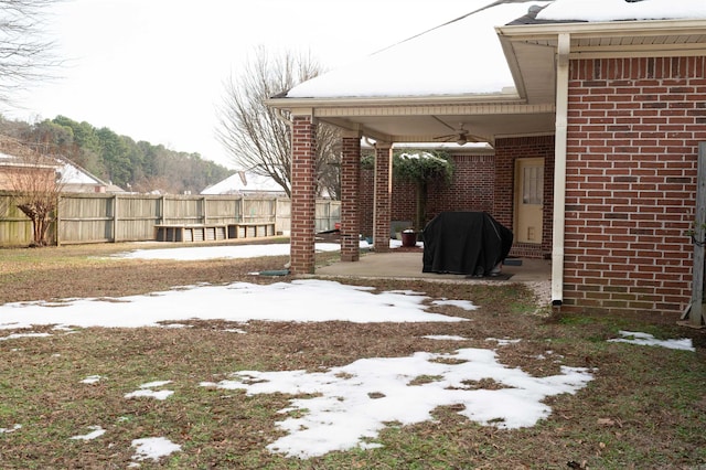 yard covered in snow with a patio and ceiling fan