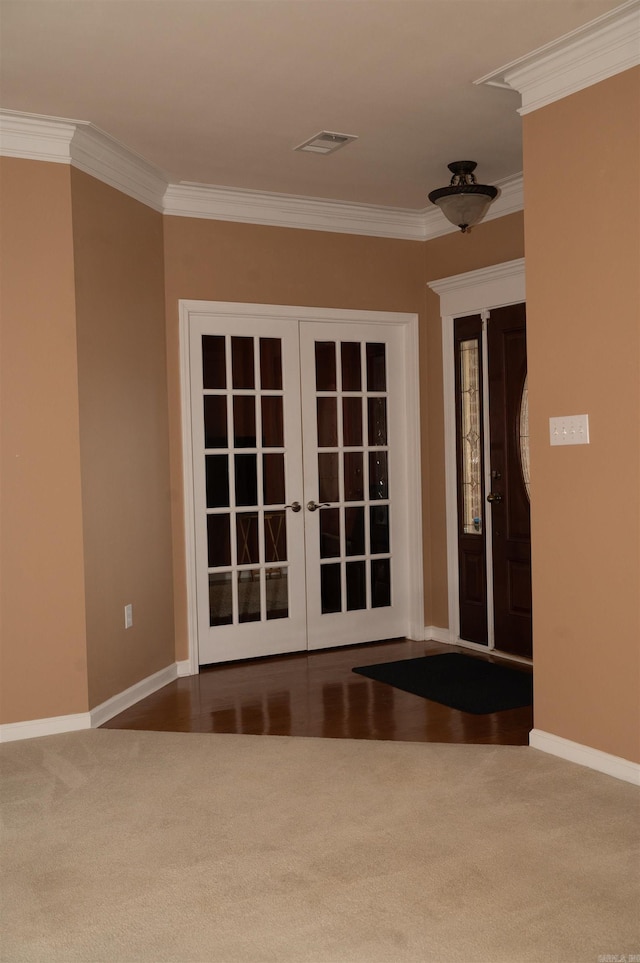 entrance foyer with french doors, crown molding, and dark carpet