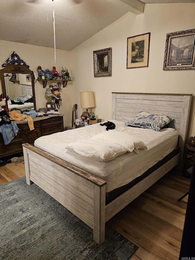 bedroom featuring hardwood / wood-style flooring, a textured ceiling, ceiling fan, and lofted ceiling with beams