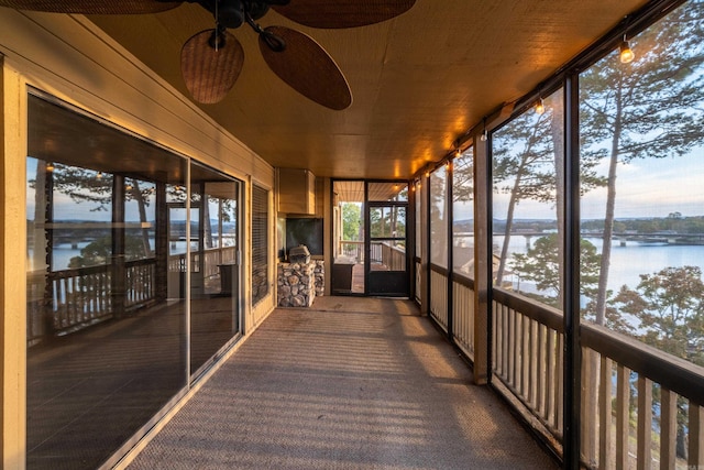 unfurnished sunroom with ceiling fan, wooden ceiling, and a water view