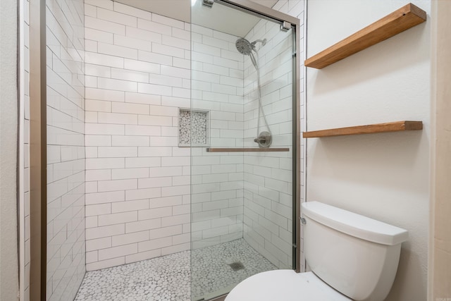 bathroom featuring tiled shower and toilet