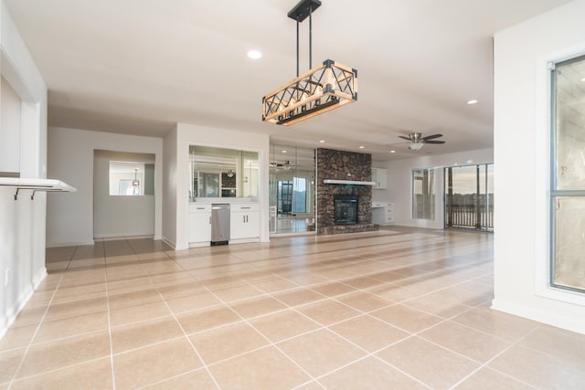 unfurnished living room with ceiling fan, a fireplace, and light tile patterned floors