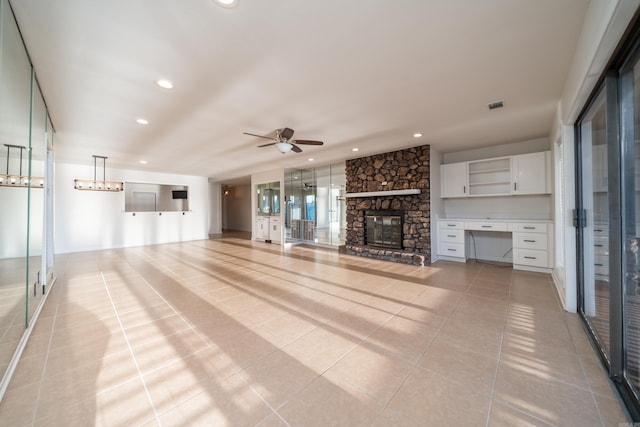 unfurnished living room with a fireplace, ceiling fan, and light tile patterned floors