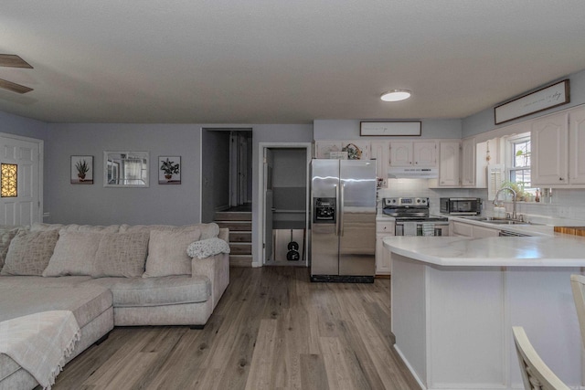 kitchen featuring appliances with stainless steel finishes, kitchen peninsula, decorative backsplash, white cabinets, and sink