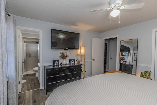 bedroom with ensuite bath, a textured ceiling, ceiling fan, and dark wood-type flooring