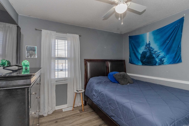 bedroom featuring a textured ceiling, ceiling fan, and light hardwood / wood-style flooring