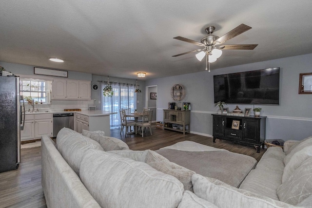 living room with sink, ceiling fan, dark hardwood / wood-style flooring, and a textured ceiling