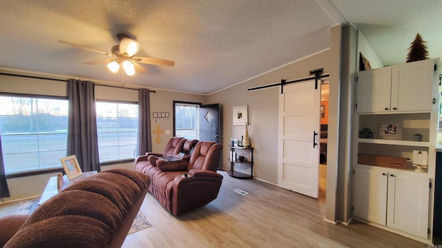 living room featuring light wood-type flooring, crown molding, vaulted ceiling, and a barn door