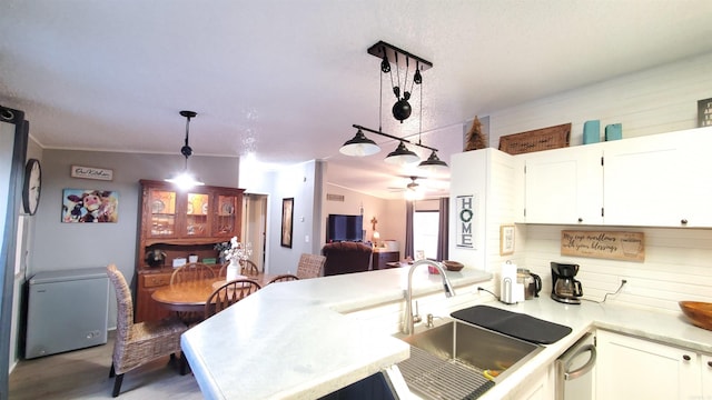 kitchen featuring kitchen peninsula, decorative light fixtures, white cabinetry, ceiling fan, and sink