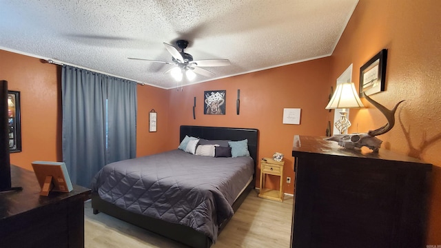 bedroom with ceiling fan, light wood-type flooring, crown molding, and a textured ceiling