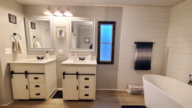 bathroom featuring a textured ceiling, a tub to relax in, vanity, and hardwood / wood-style flooring