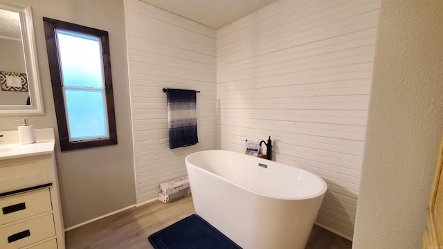 bathroom with hardwood / wood-style floors, a washtub, and vanity