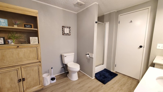 bathroom featuring toilet, a textured ceiling, hardwood / wood-style floors, a shower with shower door, and vanity