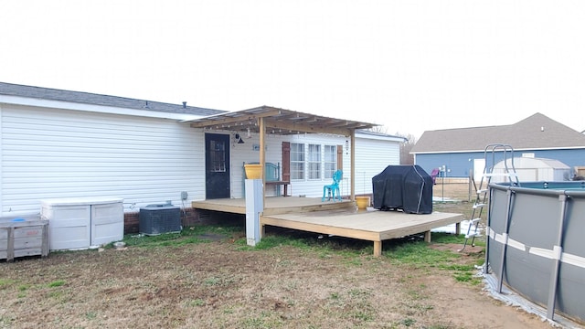 rear view of property featuring a pergola, a swimming pool side deck, and central AC unit