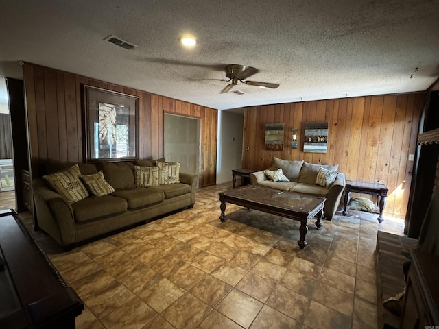 living room with wood walls, ceiling fan, and a textured ceiling