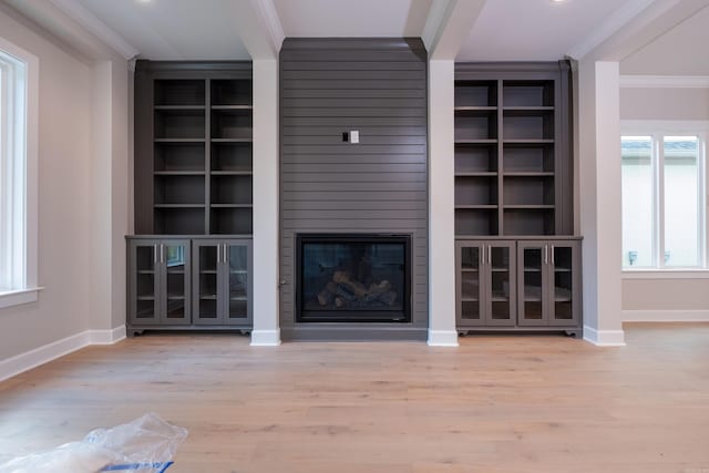 unfurnished living room featuring ornamental molding, a fireplace, built in features, and light hardwood / wood-style flooring