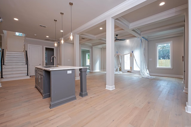 kitchen featuring hanging light fixtures, a kitchen island with sink, ceiling fan, crown molding, and beam ceiling