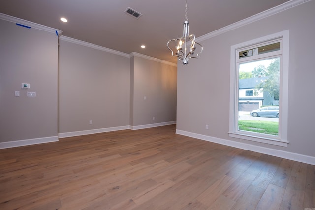 unfurnished room featuring crown molding, a chandelier, hardwood / wood-style floors, and a wealth of natural light