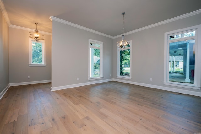 empty room with crown molding, a healthy amount of sunlight, an inviting chandelier, and light wood-type flooring