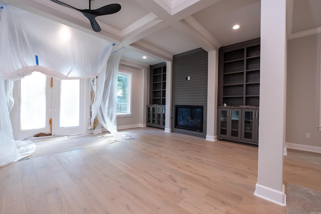 unfurnished living room with coffered ceiling, light wood-type flooring, ornamental molding, built in features, and a fireplace