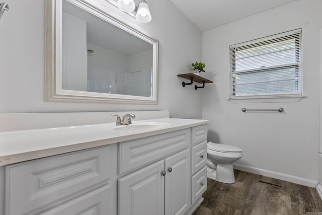 bathroom with toilet, wood-type flooring, vanity, and walk in shower