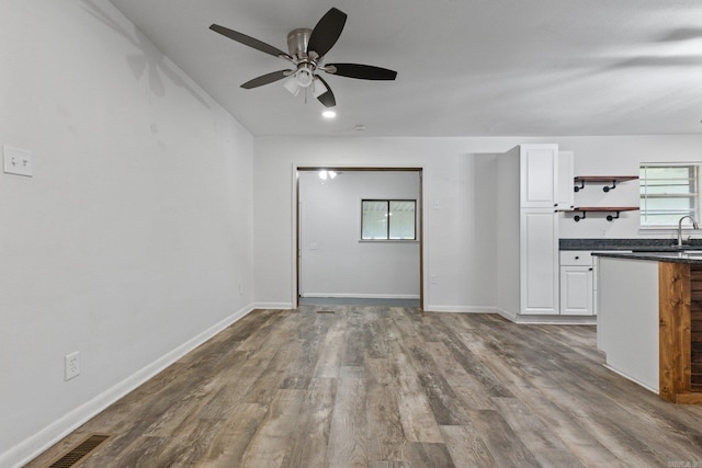 unfurnished living room featuring wood-type flooring and ceiling fan