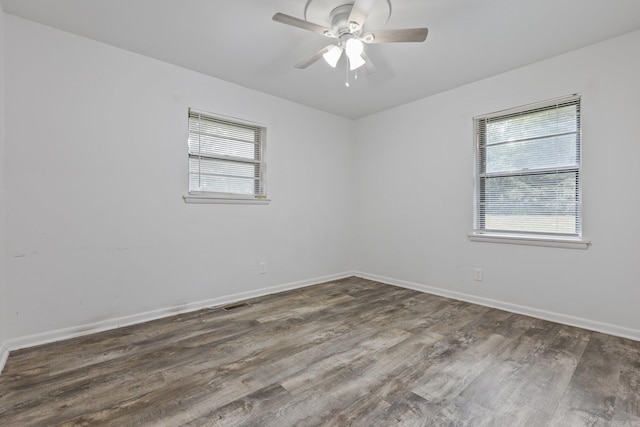 spare room featuring dark hardwood / wood-style flooring, ceiling fan, and a healthy amount of sunlight