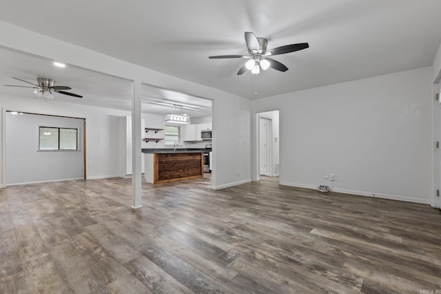 unfurnished living room featuring sink, ceiling fan, and dark wood-type flooring