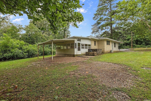 rear view of property with a carport, a sunroom, and a lawn