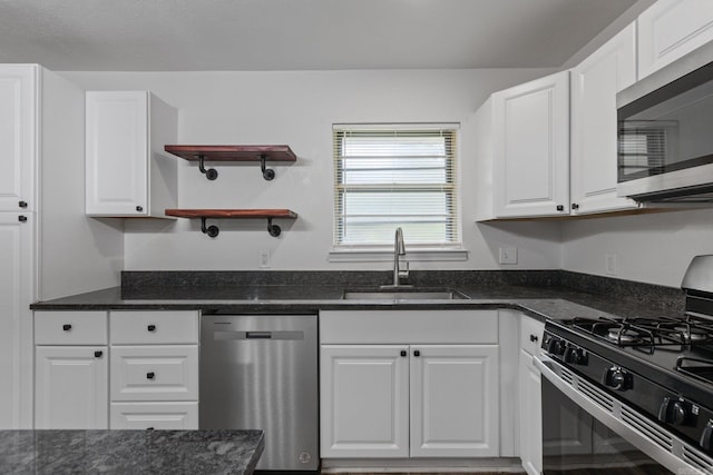 kitchen with stainless steel appliances, dark stone countertops, white cabinets, and sink