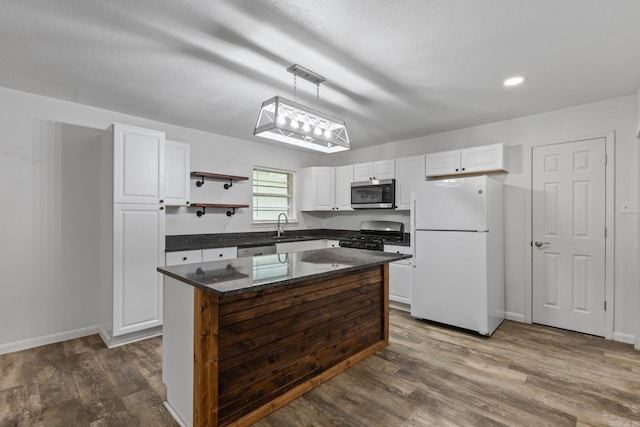 kitchen featuring appliances with stainless steel finishes, white cabinets, decorative light fixtures, and a center island