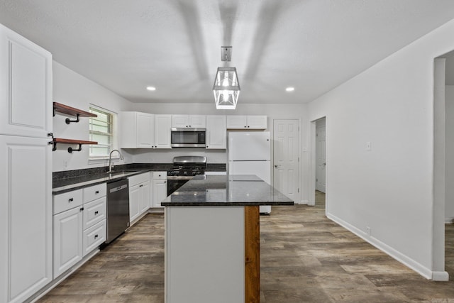 kitchen with dark wood-type flooring, stainless steel appliances, a kitchen island, white cabinets, and sink